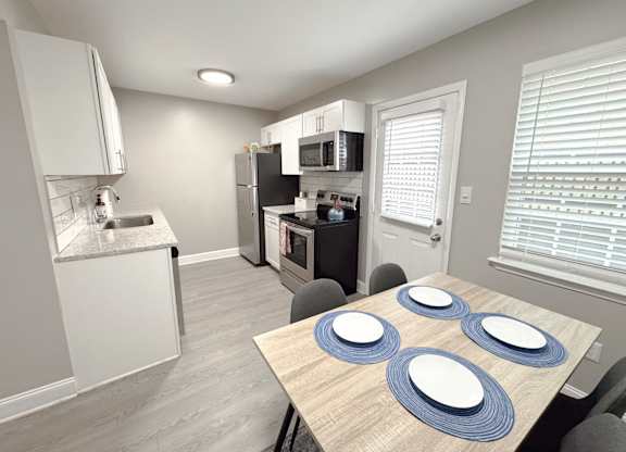 Reserve at Hillcrest Townhomes furnished kitchen with granite countertops, stainless steel appliances, and a dining room table.