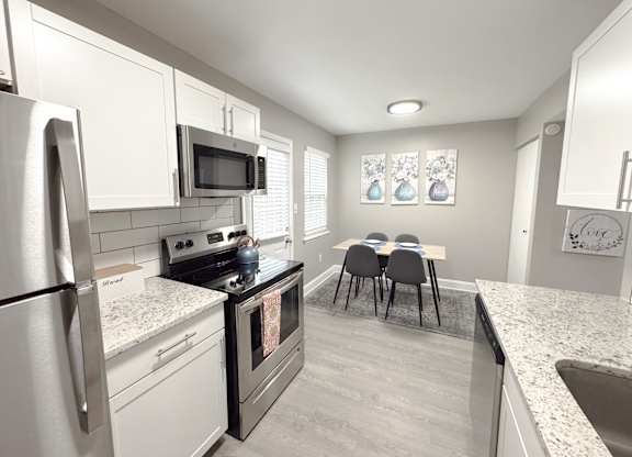 Reserve at Hillcrest Townhomes furnished kitchen with granite countertops, stainless steel appliances, and a dining room table.