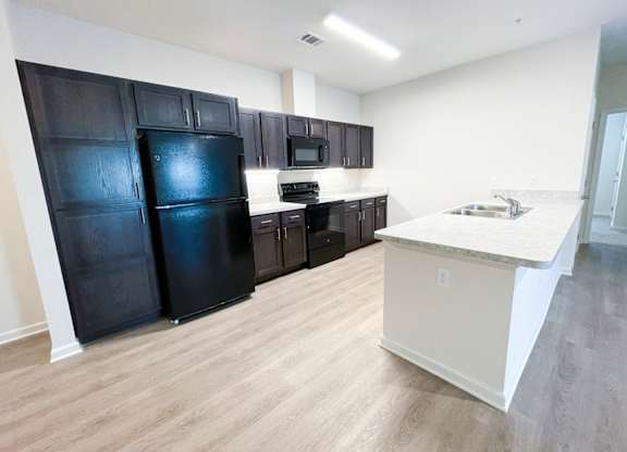 A kitchen with black appliances and wooden cabinets.