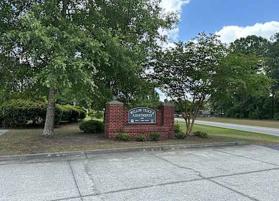 a sign on a brick wall in front of some trees