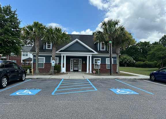 an empty parking lot in front of a building with palm trees