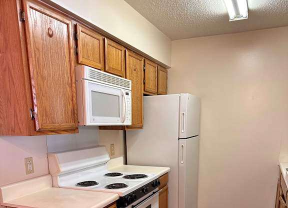 A kitchen with wooden cabinets and white appliances.