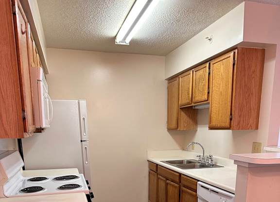 A kitchen with a white stove and wooden cabinets.