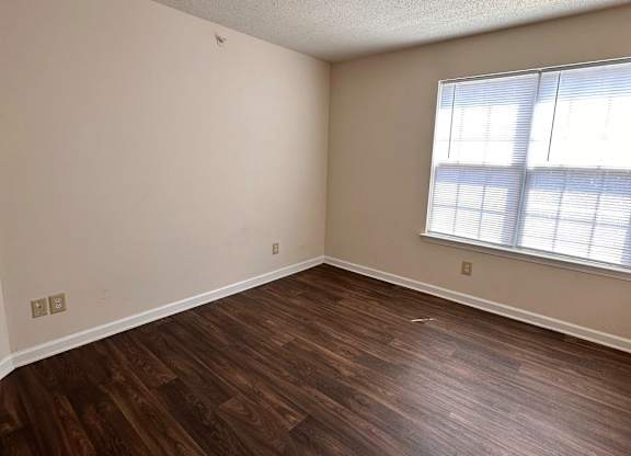 A room with wooden flooring and a window.