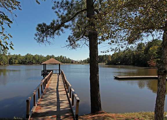 A wooden pier extends into a calm lake surrounded by trees.