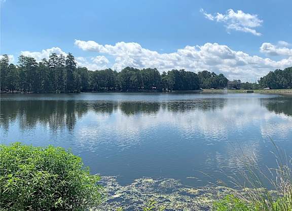 A serene lake surrounded by lush greenery under a clear sky.