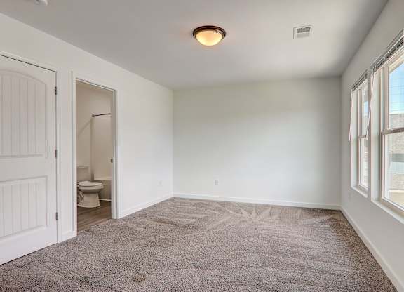 an empty living room with a door to a bathroom