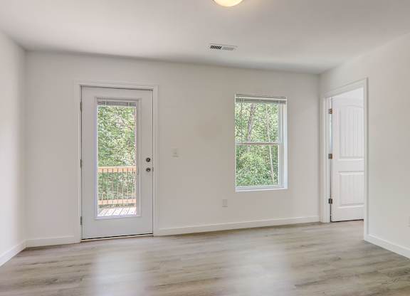 an empty living room with white walls and a door and window