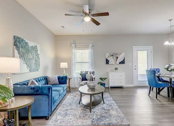 a living room with blue furniture and a ceiling fan