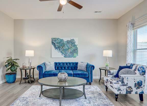 a living room with blue furniture and a ceiling fan