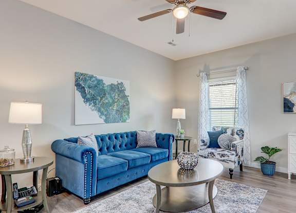 a living room with a blue couch and a ceiling fan
