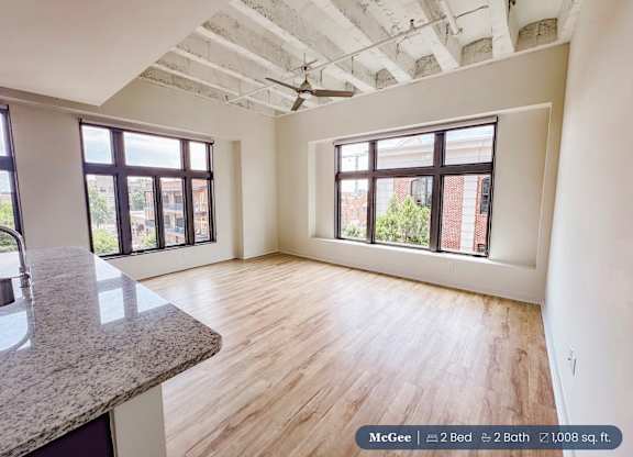 A room with a ceiling fan and two windows.