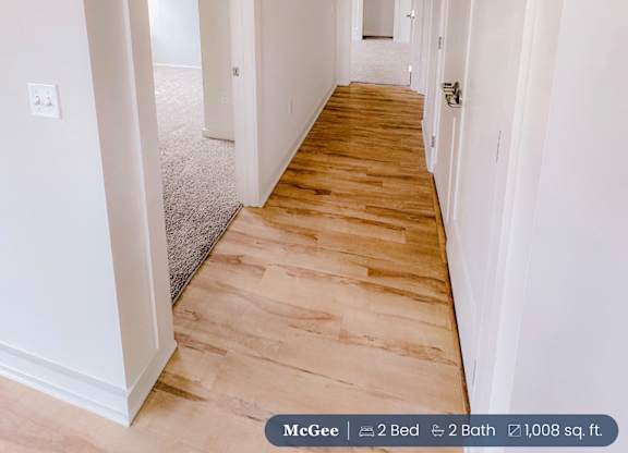 A long hallway with wood floors and white walls.