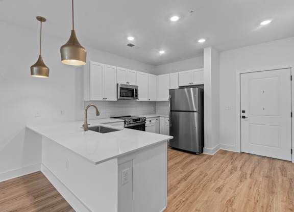 A modern kitchen with a white countertop and wooden flooring.