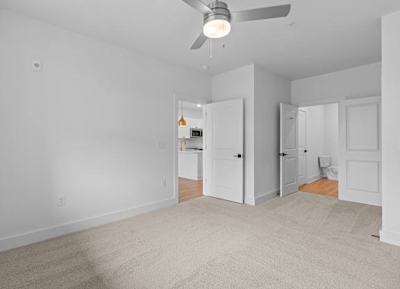 A room with a ceiling fan and carpeted floor.