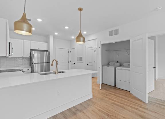 A modern kitchen with white cabinets and a wooden floor.