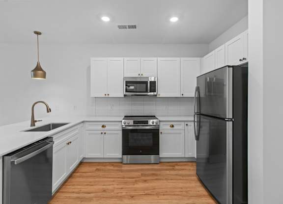 A modern kitchen with white cabinets and stainless steel appliances.