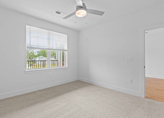 A room with a ceiling fan and a window with blinds.