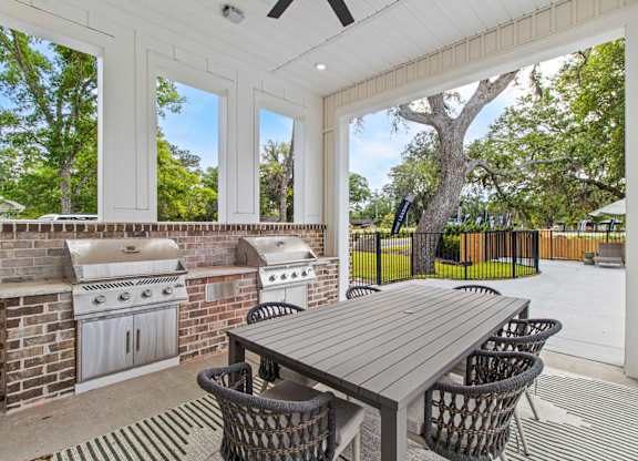 A patio with a table and chairs and a grill.