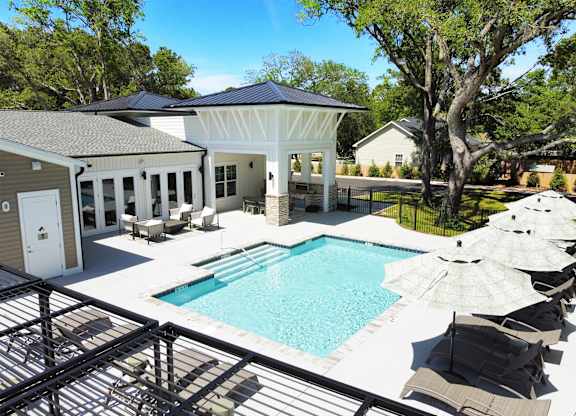 A pool with a black railing and a white umbrella.