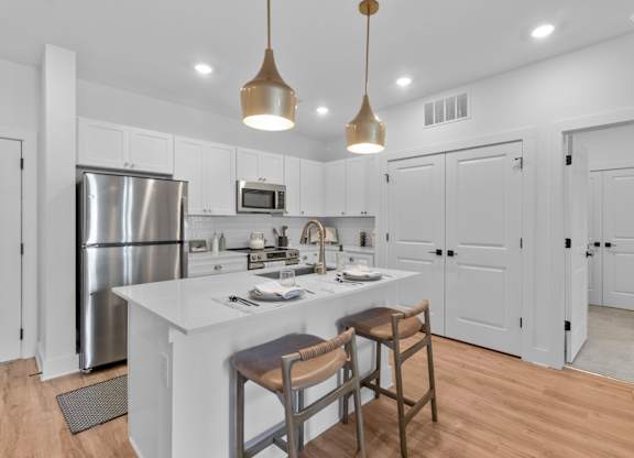 A modern kitchen with a white island and wooden stools.