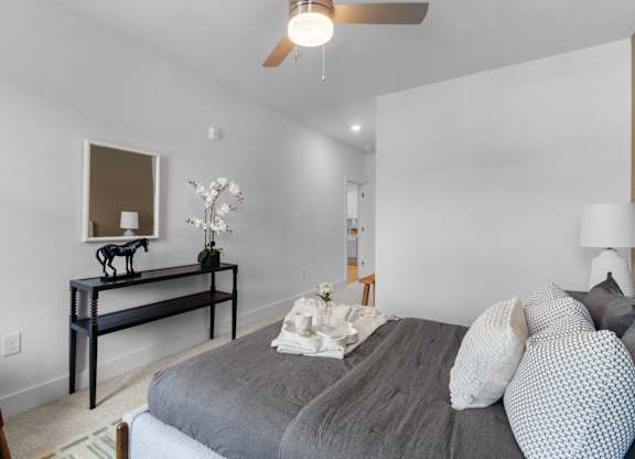 A bedroom with a bed, a chair, and a table with a horse statue on it.