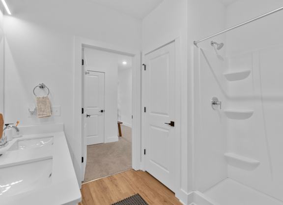 A white bathroom with a sink, mirror, and stairs.