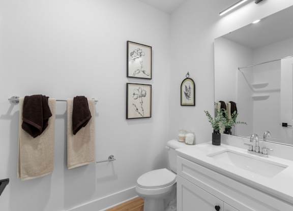 A white bathroom with a toilet, sink, and towels.