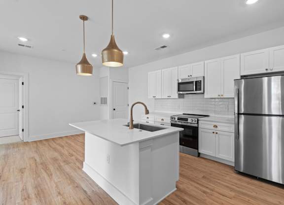 A modern kitchen with a white island and stainless steel appliances.