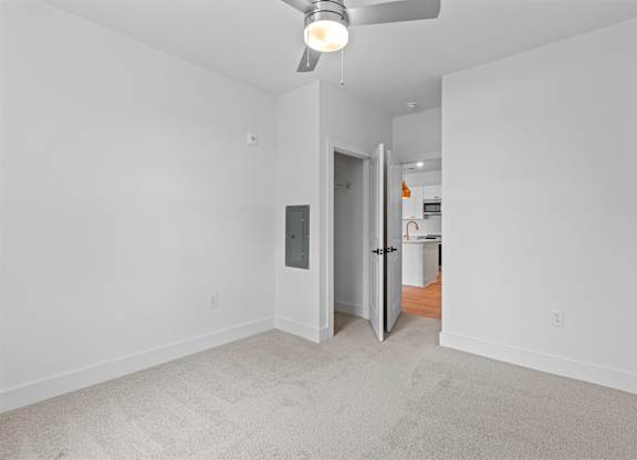 A room with a ceiling fan and a door leading to another room.