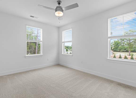 A room with a ceiling fan and two windows.