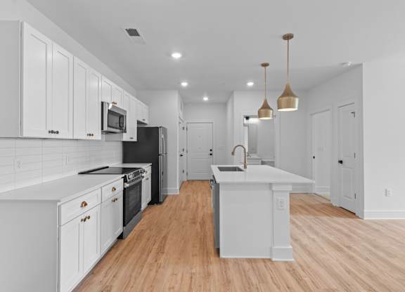 A modern kitchen with white cabinets and a black refrigerator.