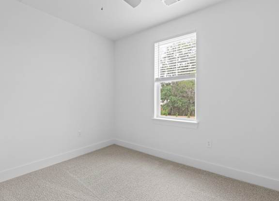 A room with a window showing a view of trees outside.