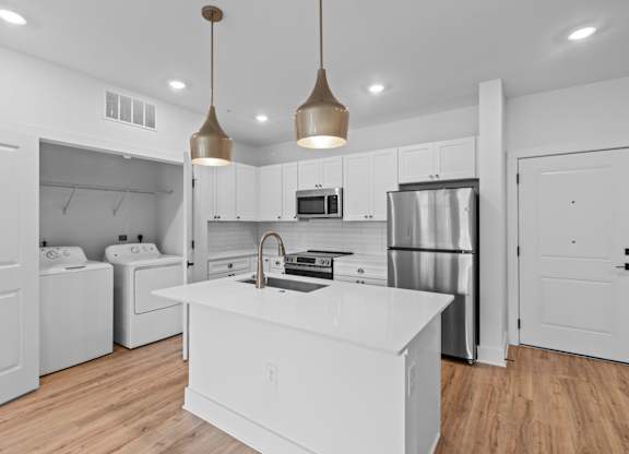 A modern kitchen with a white island and stainless steel appliances.