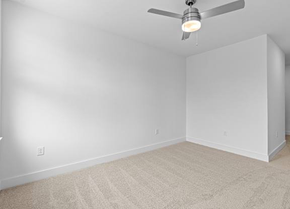A room with a ceiling fan and carpeted floor.