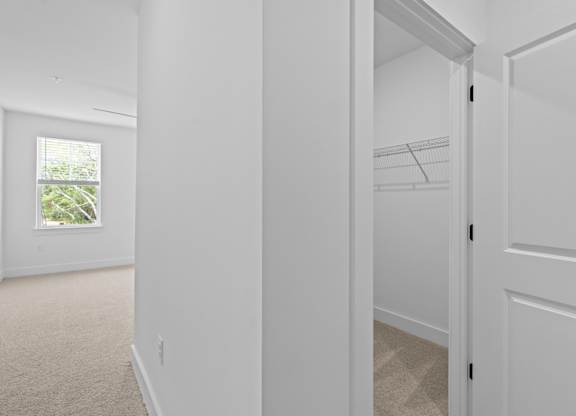 A white hallway with a door on the right and a window on the left.