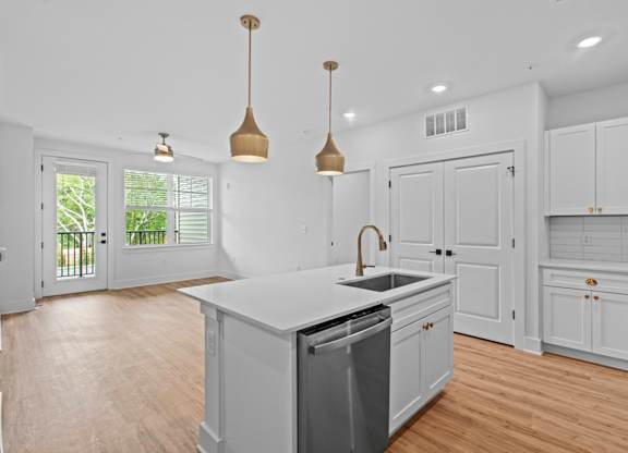 A kitchen with white cabinets and a wooden floor.