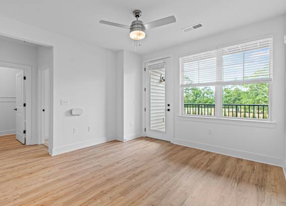 A room with a ceiling fan and wooden flooring.