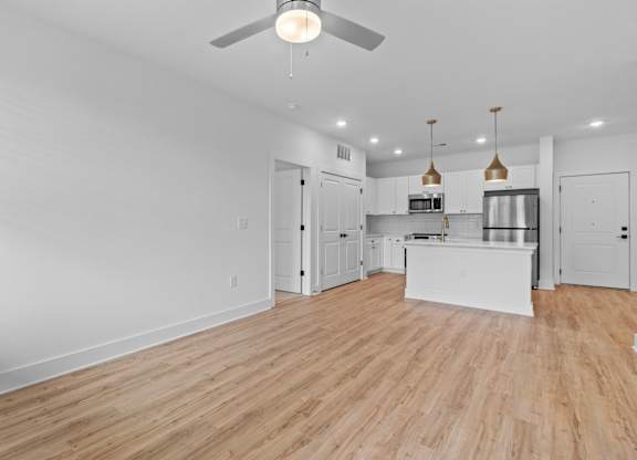 A spacious kitchen and living room with wooden floors and white walls.