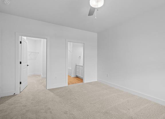 A white room with a carpet and a ceiling fan.