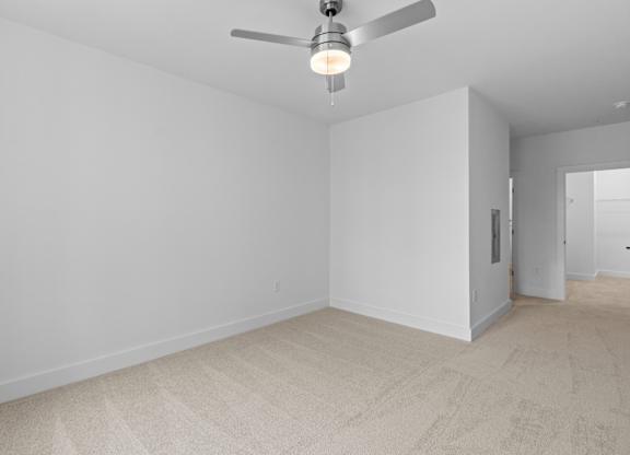 A room with a ceiling fan and carpeted floor.