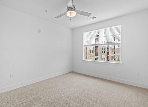A room with a ceiling fan and a window with blinds.