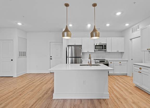 A modern kitchen with a center island and pendant lights.