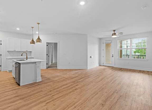 A spacious kitchen with wooden floors and white walls.