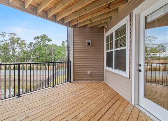A wooden deck with a sliding glass door leading to a patio.