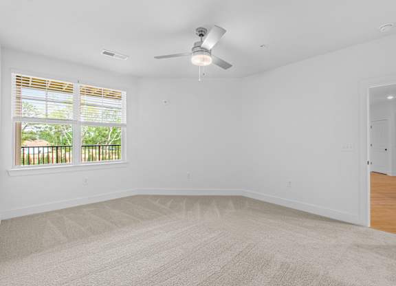 A room with a ceiling fan and carpeted floor.