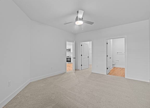A room with a ceiling fan and carpeted floor.