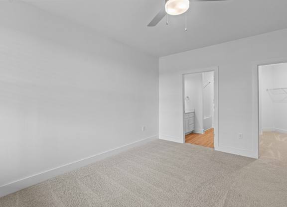 A room with a ceiling fan and carpeted floor.