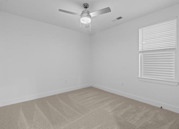 A room with a ceiling fan and carpeted floor.