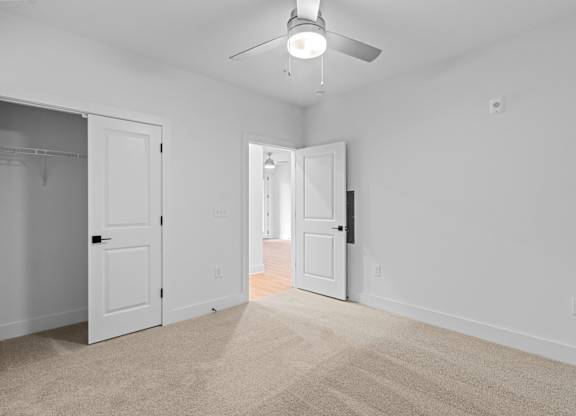 A room with a carpeted floor and a ceiling fan.